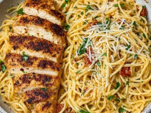 Garlic butter chicken pasta in a large skillet with sliced chicken breast, spaghetti, and Parmesan cheese garnished with fresh parsley