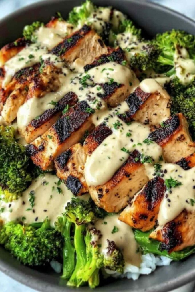 Grilled chicken and broccoli bowls with creamy garlic sauce over brown rice in white bowl