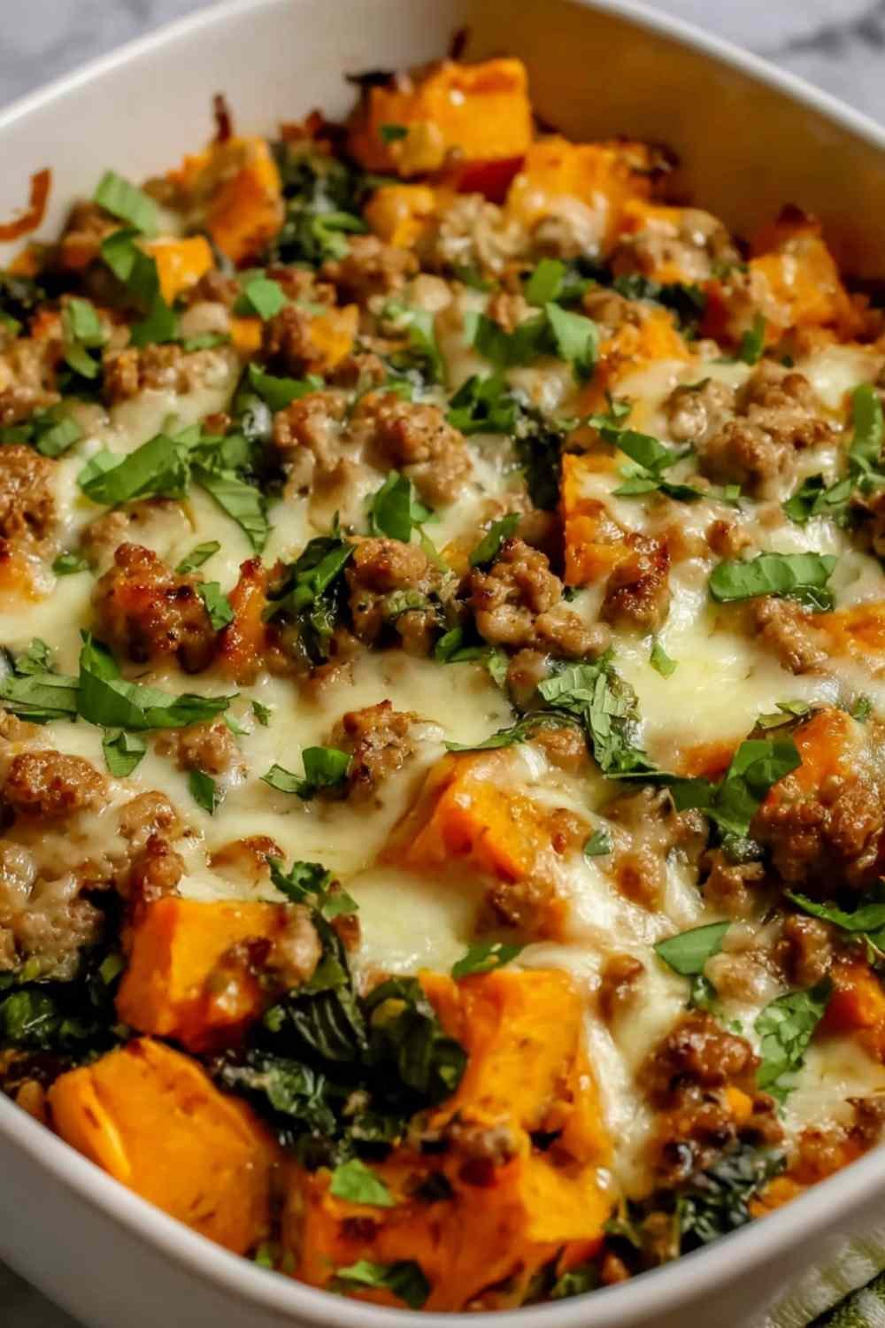Healthy ground turkey sweet potato bake in a white baking dish with melted cheddar and golden roasted sweet potatoes