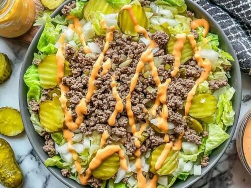 High protein cheeseburger bowl with seasoned ground beef, cheddar cheese, pickles, and creamy Big Mac sauce over chopped lettuce