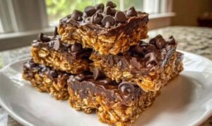 Easy No-Bake Homemade Protein Bars Stack of chewy homemade protein bars with dark chocolate topping on white parchment paper