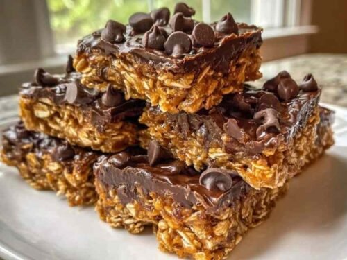 Stack of chewy homemade protein bars with dark chocolate topping on white parchment paper