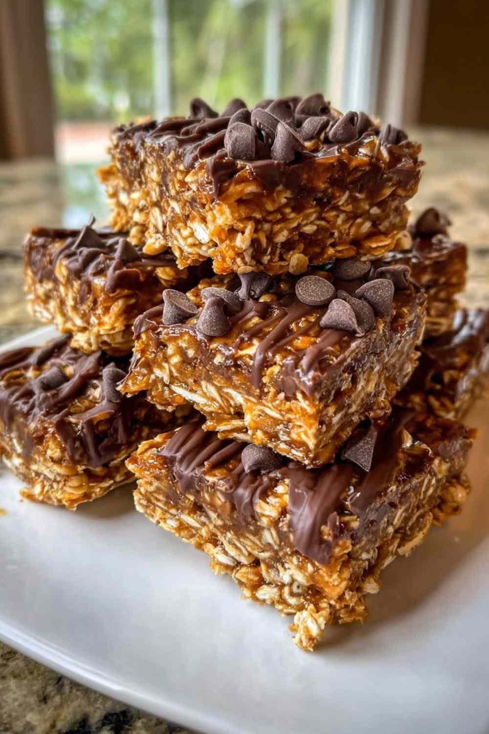 Stack of chewy homemade protein bars with dark chocolate topping on white parchment paper