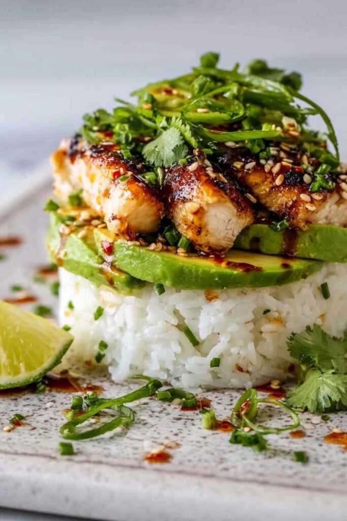 Honey Lime Chicken Avocado Rice Stack in a white bowl with grilled chicken strips, avocado slices, black beans, corn, cilantro, and honey lime dressing