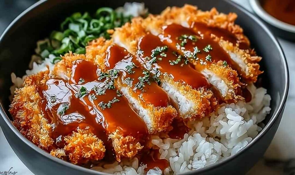 Japanese katsu bowl with sliced crispy panko chicken over white rice, shredded cabbage, and homemade tonkatsu sauce