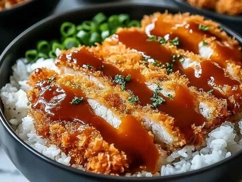 Japanese katsu bowl with sliced crispy panko chicken over white rice, shredded cabbage, and homemade tonkatsu sauce