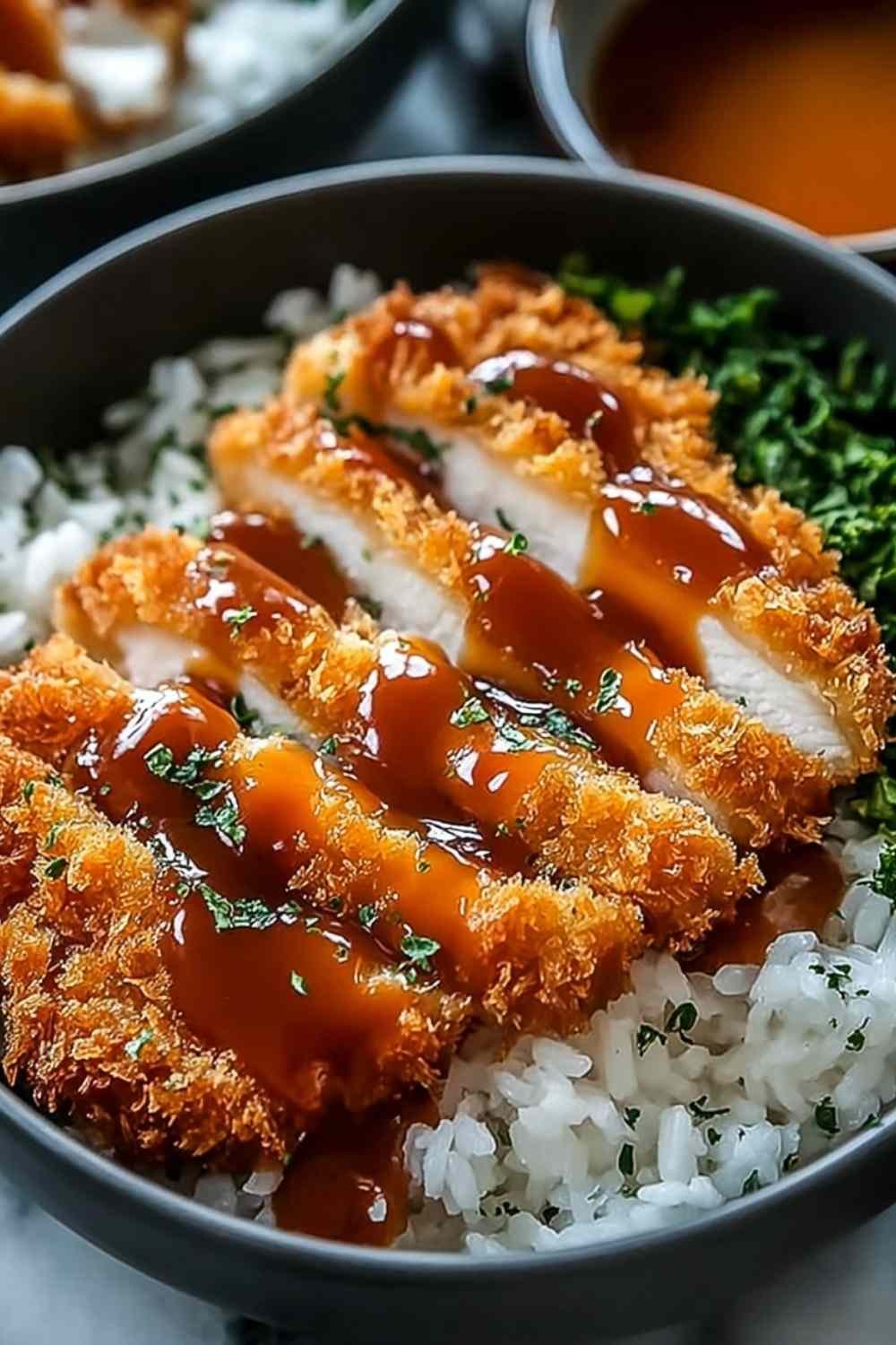 Japanese katsu bowl with sliced crispy panko chicken over white rice, shredded cabbage, and homemade tonkatsu sauce