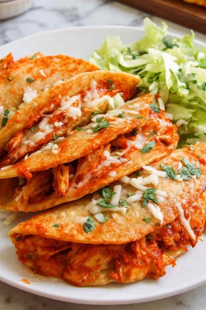 Crispy baked chicken tacos golden brown on a parchment lined baking sheet fresh out of the oven