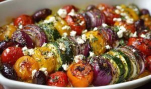 One pan Greek vegetables with roasted bell peppers, zucchini, burst cherry tomatoes, Kalamata olives, and crumbled feta on a sheet pan