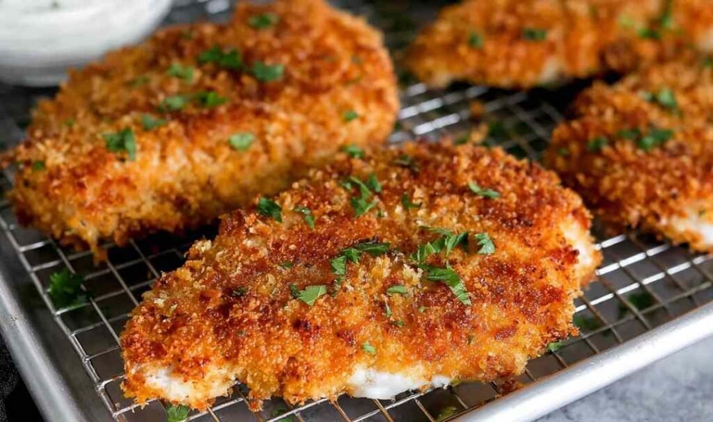 Crispy panko crusted chicken breasts resting on a wire rack after pan-frying, golden brown crust visible