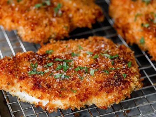 Crispy panko crusted chicken breasts resting on a wire rack after pan-frying, golden brown crust visible