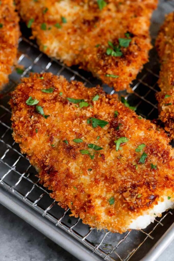 Crispy panko crusted chicken breasts resting on a wire rack after pan-frying, golden brown crust visible