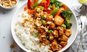 Bowl of peanut butter chicken with stir-fried vegetables served over white rice