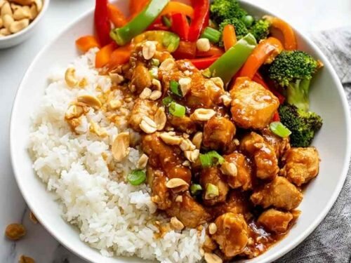 Bowl of peanut butter chicken with stir-fried vegetables served over white rice
