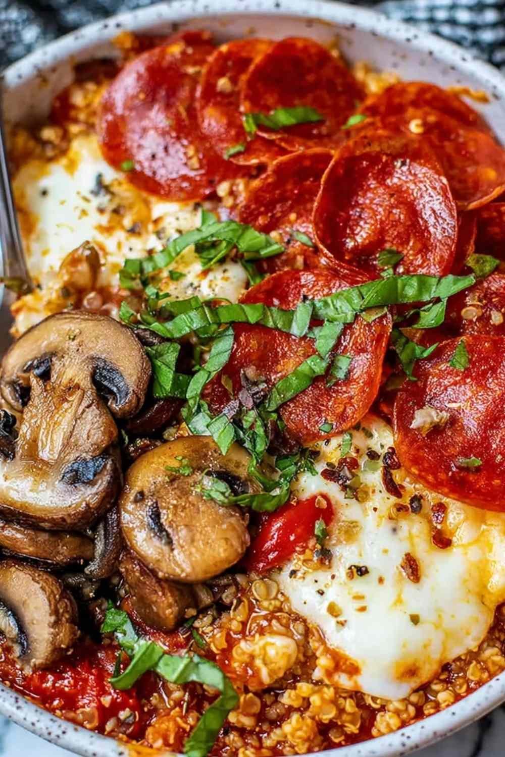 Pizza protein bowl with bubbling melted mozzarella and pepperoni on a quinoa mushroom base in a white bowl