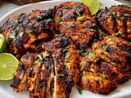 Sliced Pollo Asado Chipotle copycat chicken on a wooden board with lime wedges and fresh cilantro