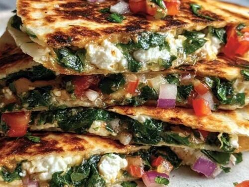 Crispy Mediterranean quesadillas sliced into wedges on a wooden board served with tzatziki dipping sauce