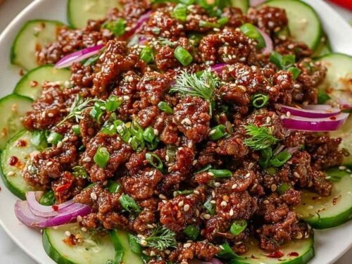 Spicy Keto Korean Ground Beef with Cucumber Salad served in a bowl over cauliflower rice with sesame seeds and green onions