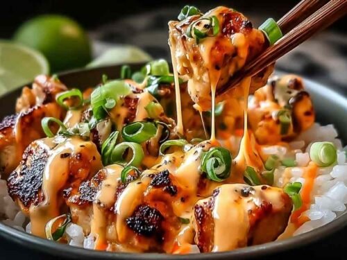 Sweet chili chicken bowl with coconut lime drizzle over jasmine rice, topped with diced tomatoes, green onions, and sesame seeds