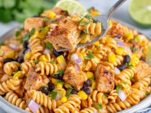 Zesty chicken enchilada pasta salad in a large white bowl with rotini, seasoned chicken, black beans, corn, and cilantro