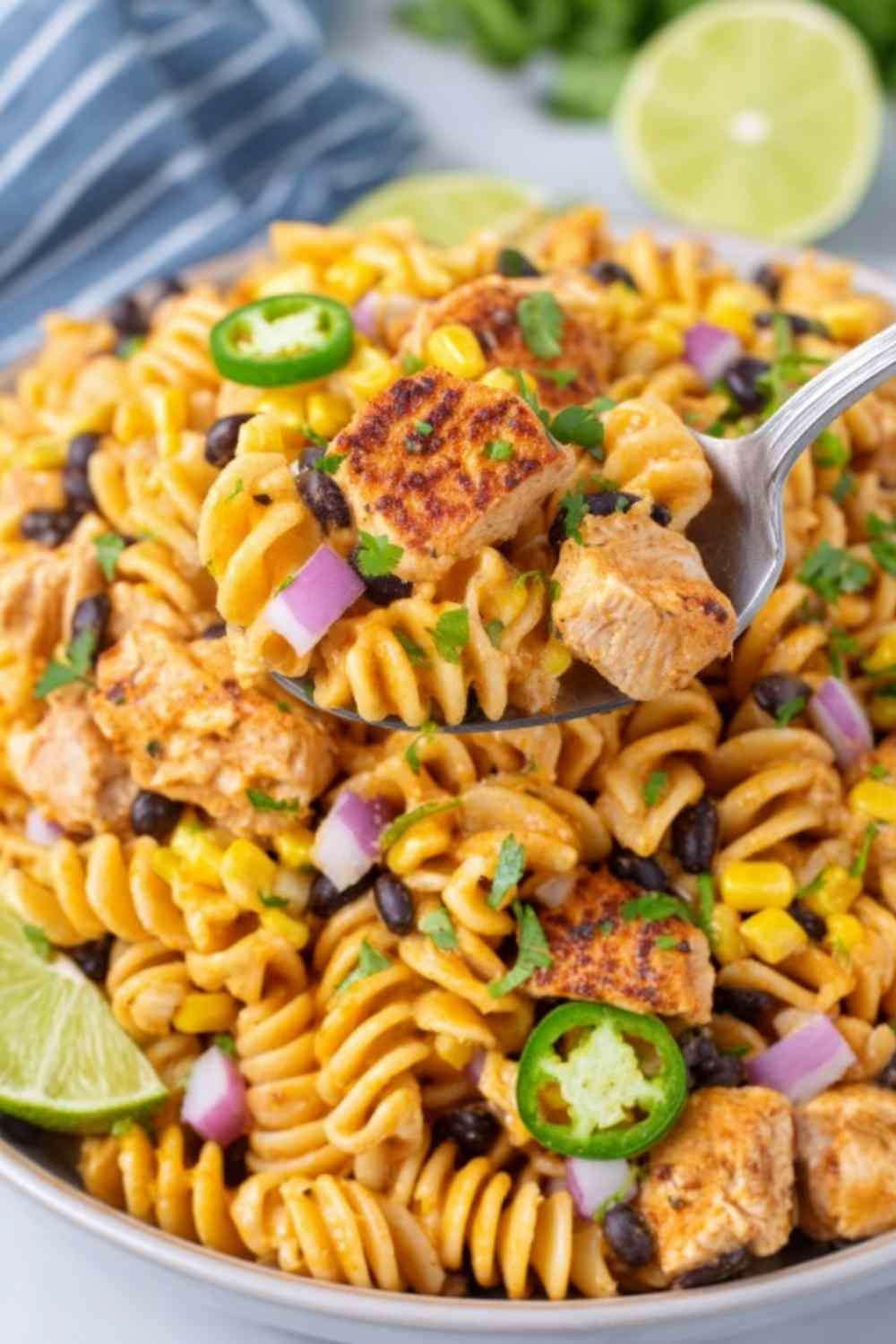 Zesty chicken enchilada pasta salad in a large white bowl with rotini, seasoned chicken, black beans, corn, and cilantro